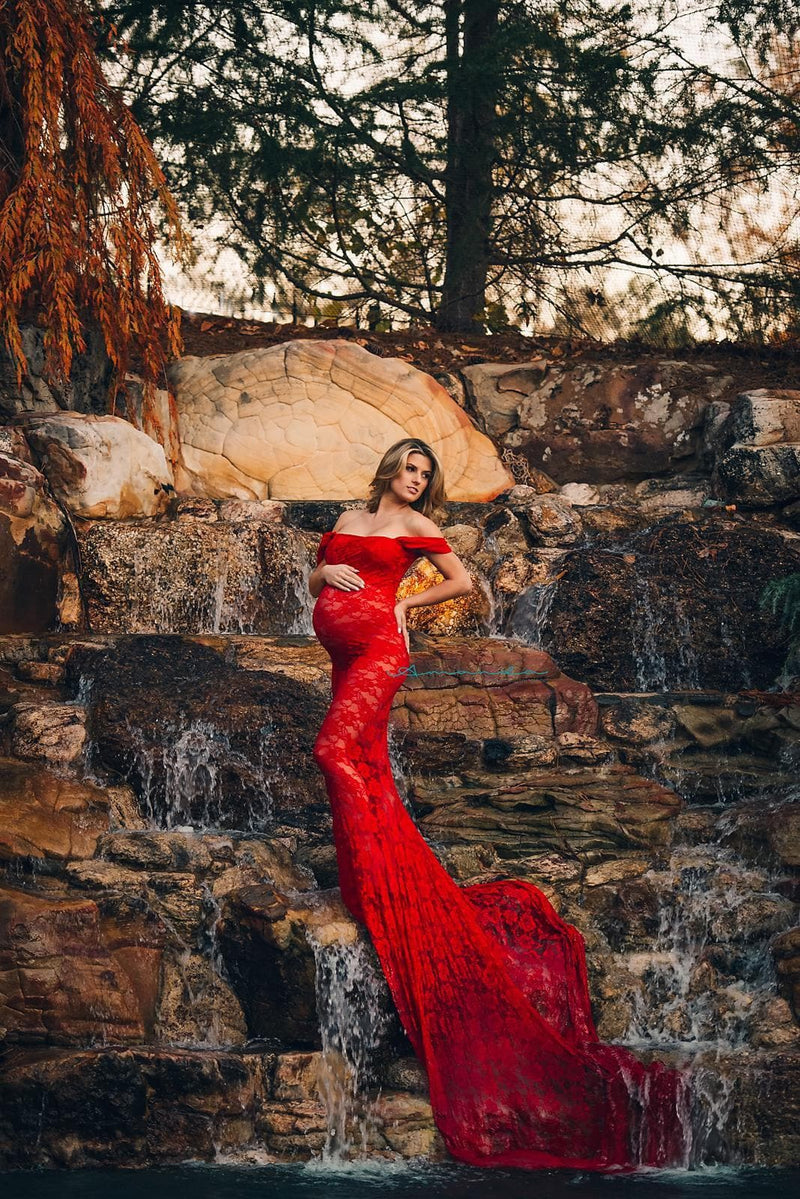 Expecting mother wearing the Catherine gown in red by Sew Trendy standing on cliff face