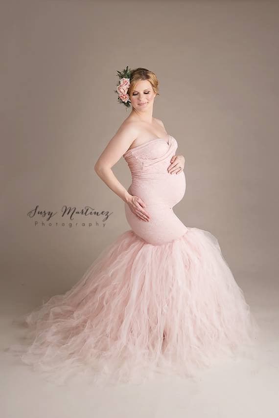 Pregnant woman wearing Celine gown in blush by Sew Trendy standing in studio on taupe backdrop