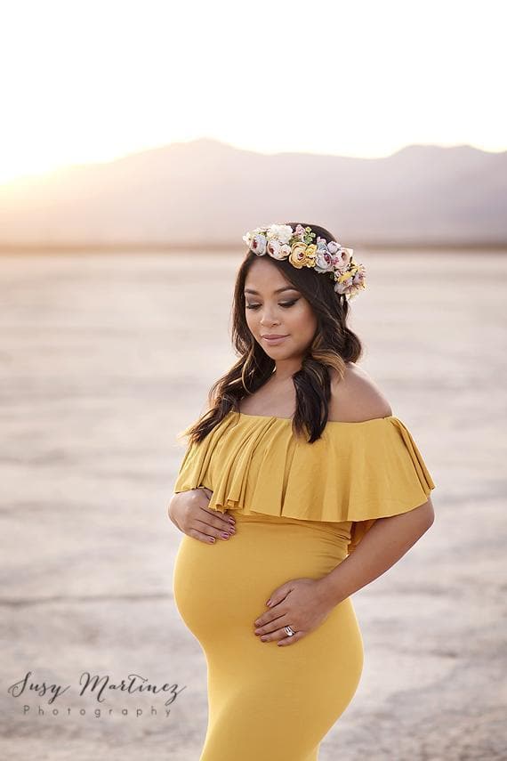 Expecting mother wearing the Colbie gown in gold by Sew Trendy standing in desert at sunset