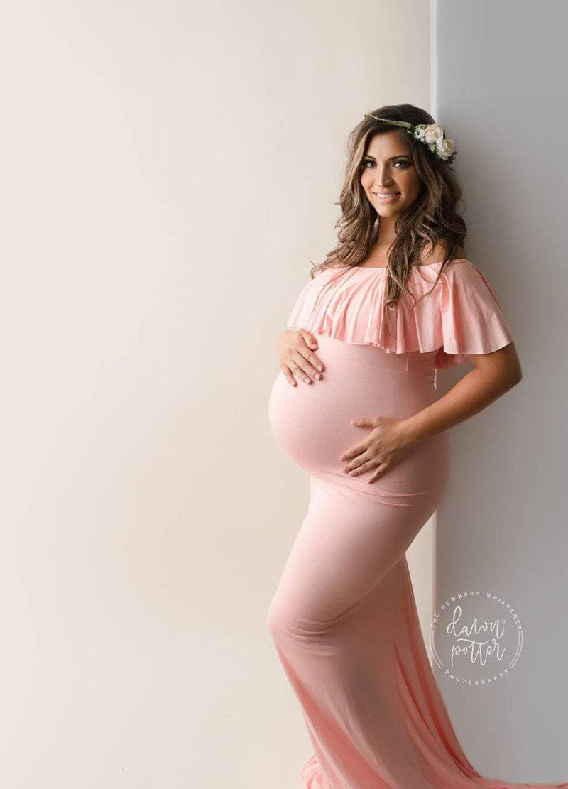 Expecting mother wearing the Colbie gown in dusty pink by Sew Trendy standing in backlit studio