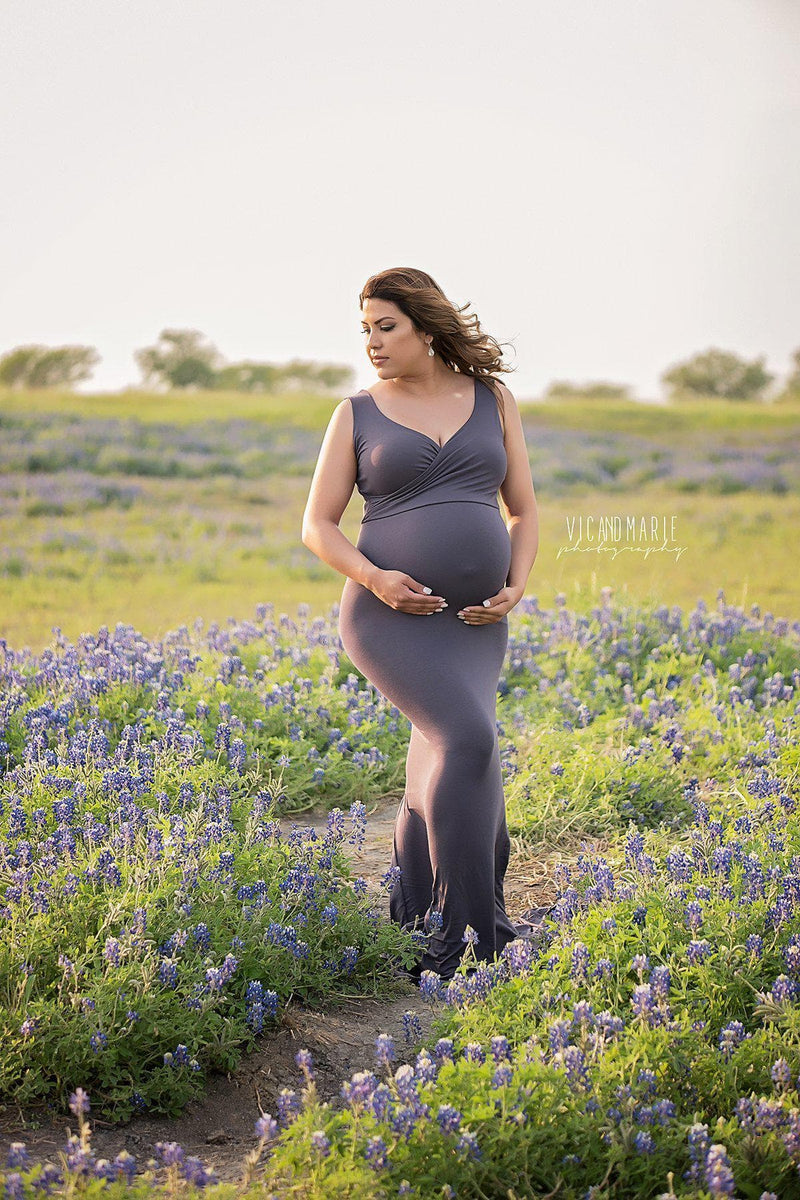 Expecting mother wearing the Courtney gown in charcoal standing in bluebonnet field