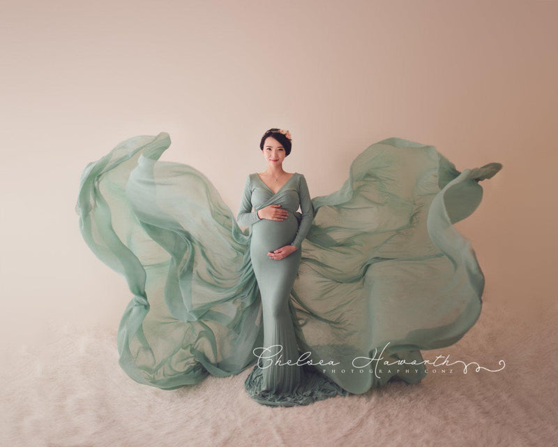 Expecting mother wearing the Emmery gown and detachable waterfall tossing train by Sew Trendy in a neutral colored photography studio