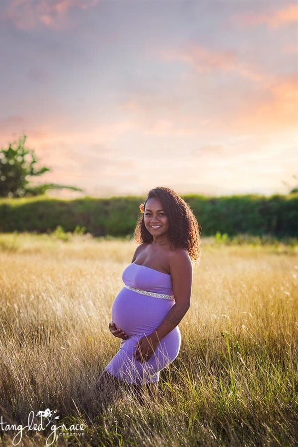 Pregnant woman wearing the Teagan fitted slip by Sew Trendy standing in sunkissed field at sunset