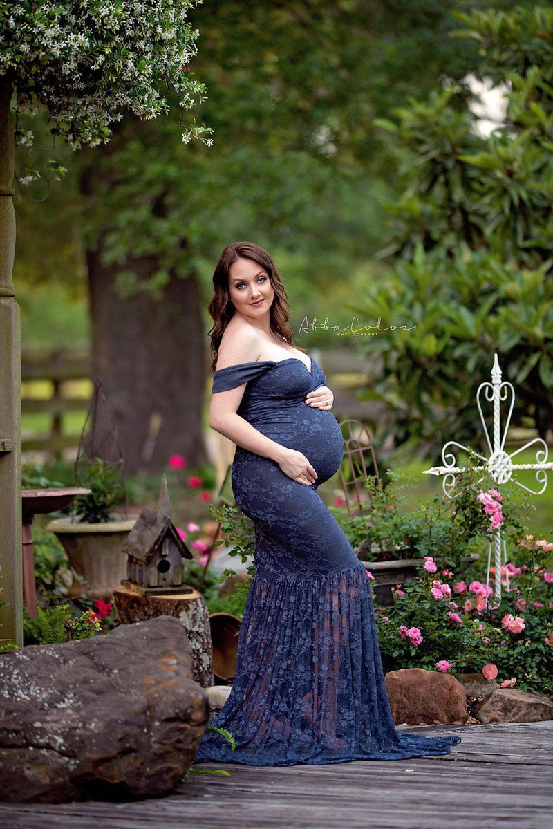 Pregnant mother in the Marilyn Gown in Navy Blue by Sew Trendy Accessories standing in a garden.
