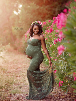 Pregnant mother in the Marilyn Gown in Evergreen by Sew Trendy Accessories standing by flowers.