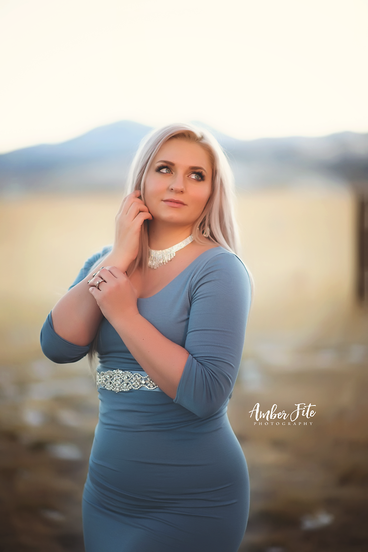 Beautiful blonde model wearing the Ember in steel blue by Sew Trendy standing in a field at dusk in winter