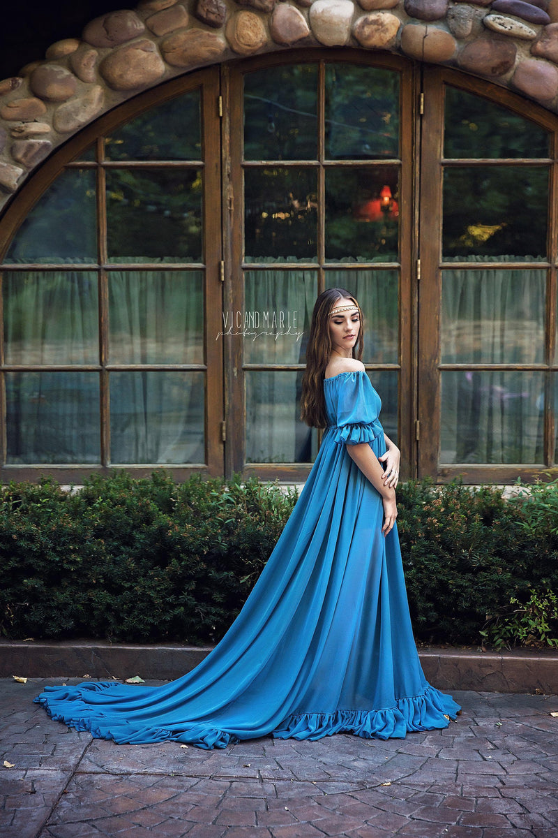 Model in the Paulina Gown in Blue Steel by Sew Trendy Accessories standing in front of windows.