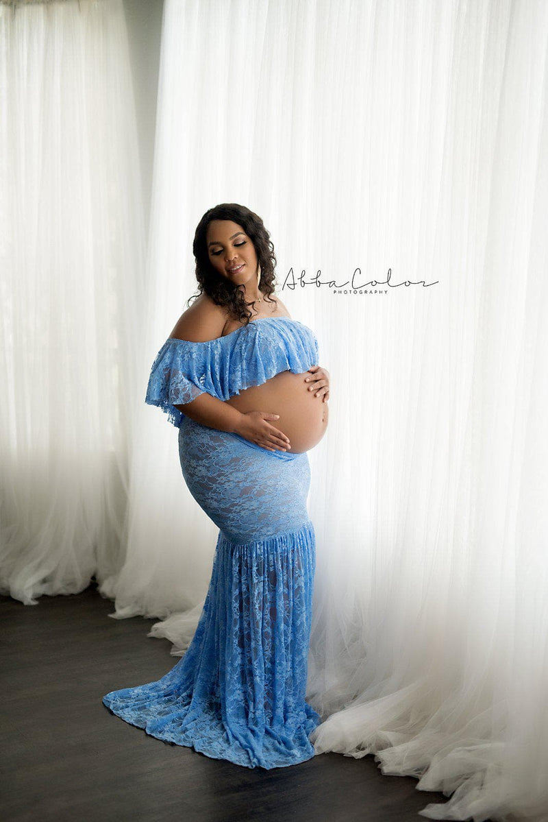 Expecting mother wearing the Casey lace maternity crop in periwinkle standing near white curtains